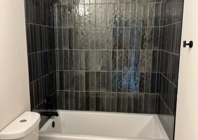 Bathroom remodel with dark subway tile tub surround