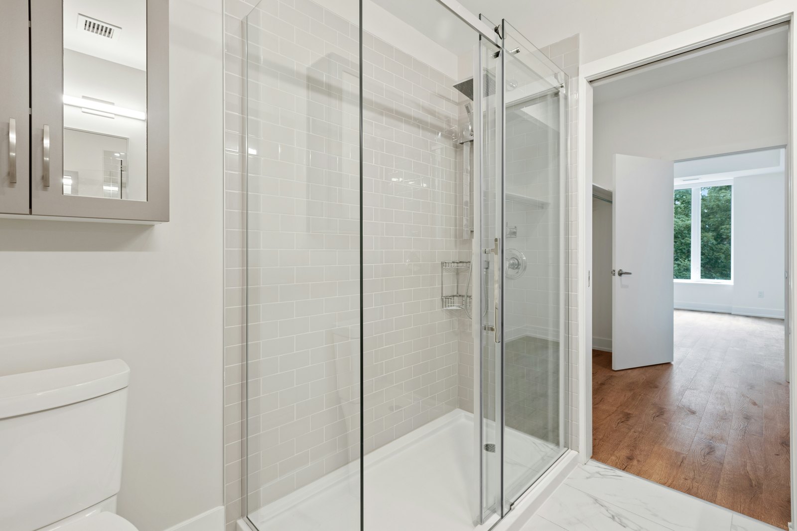 Low-threshold walk-in shower with a frameless glass enclosure and white tile